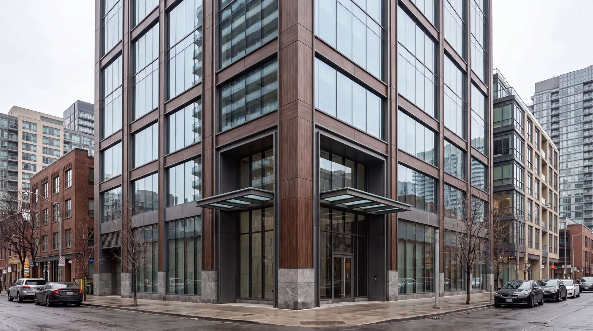 Contemporary urban office building with wood-toned cladding, expansive glazing, and a prominent corner entrance